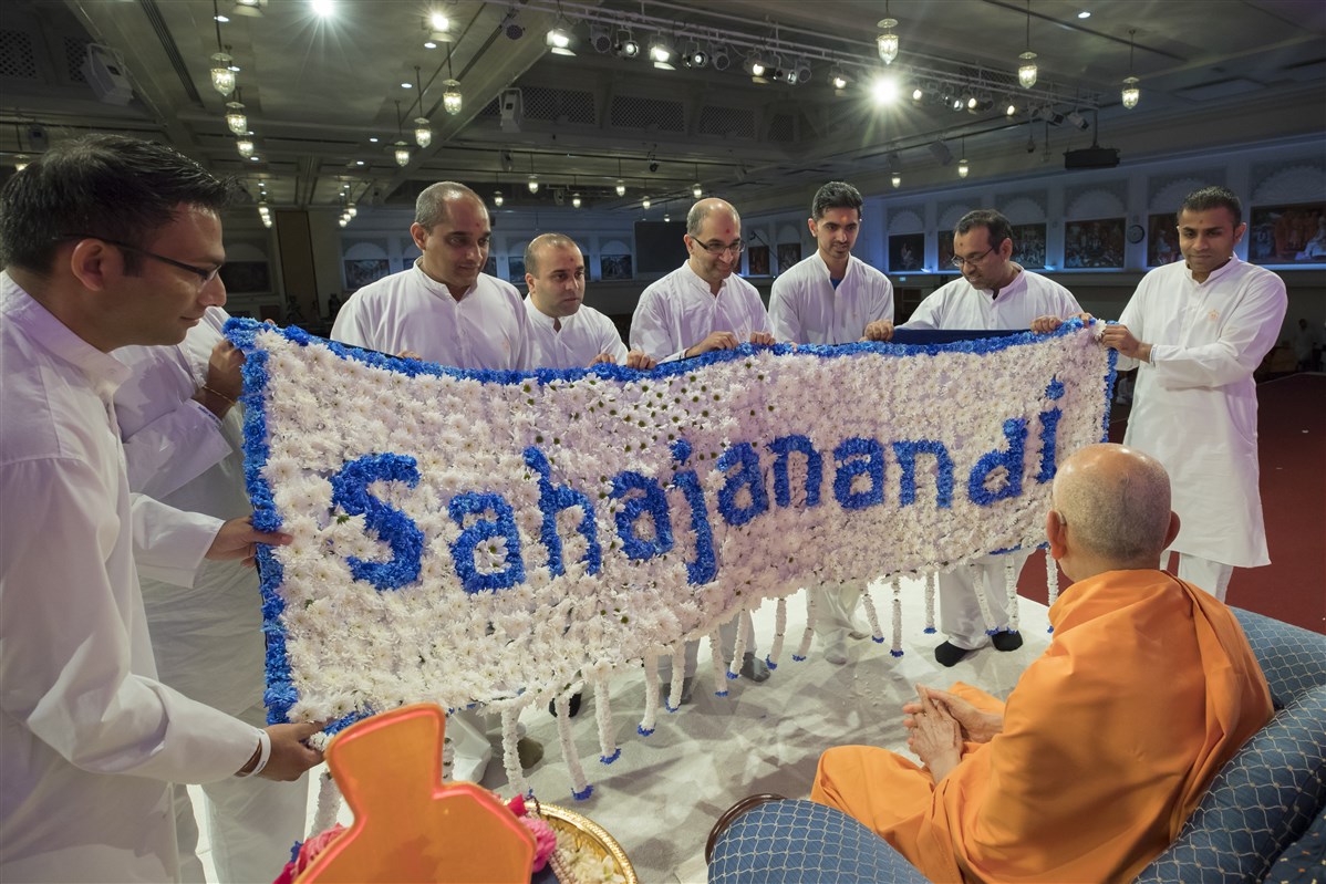 Lead Yuvak Mandal volunteers offer a shawl of fresh flowers based on the Yuvak-Yuvati Din theme, 'Sahajanandi'