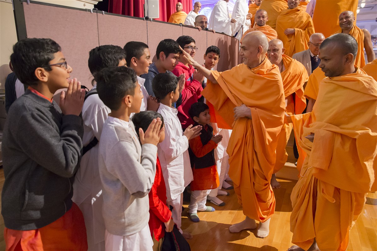 Swamishri blesses children as he departs the assembly hall