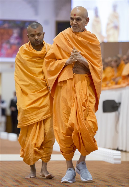 Swamishri performs his evening walk in the assembly hall, greeting devotees as he passes
