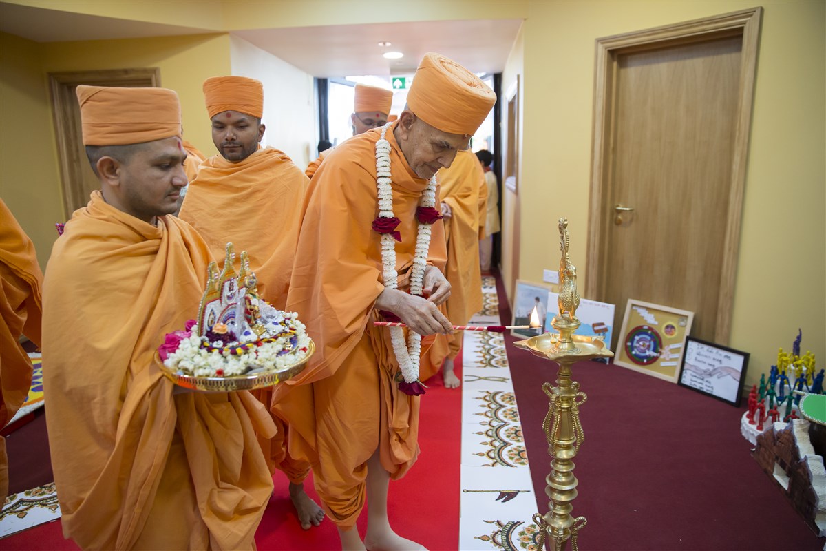 Swamishri lights a divo, marking the auspicious opening of the building
