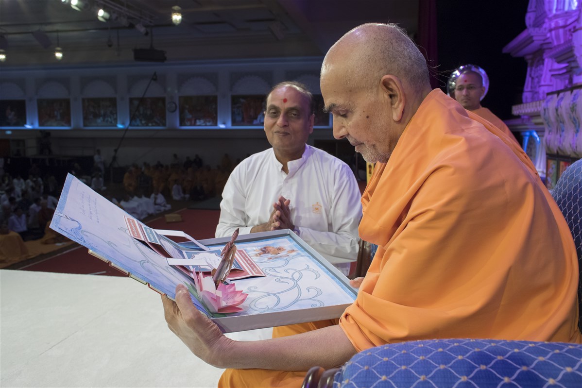 Swamishri reads a creative card presented by the 'Satsang Examinations' volunteers
