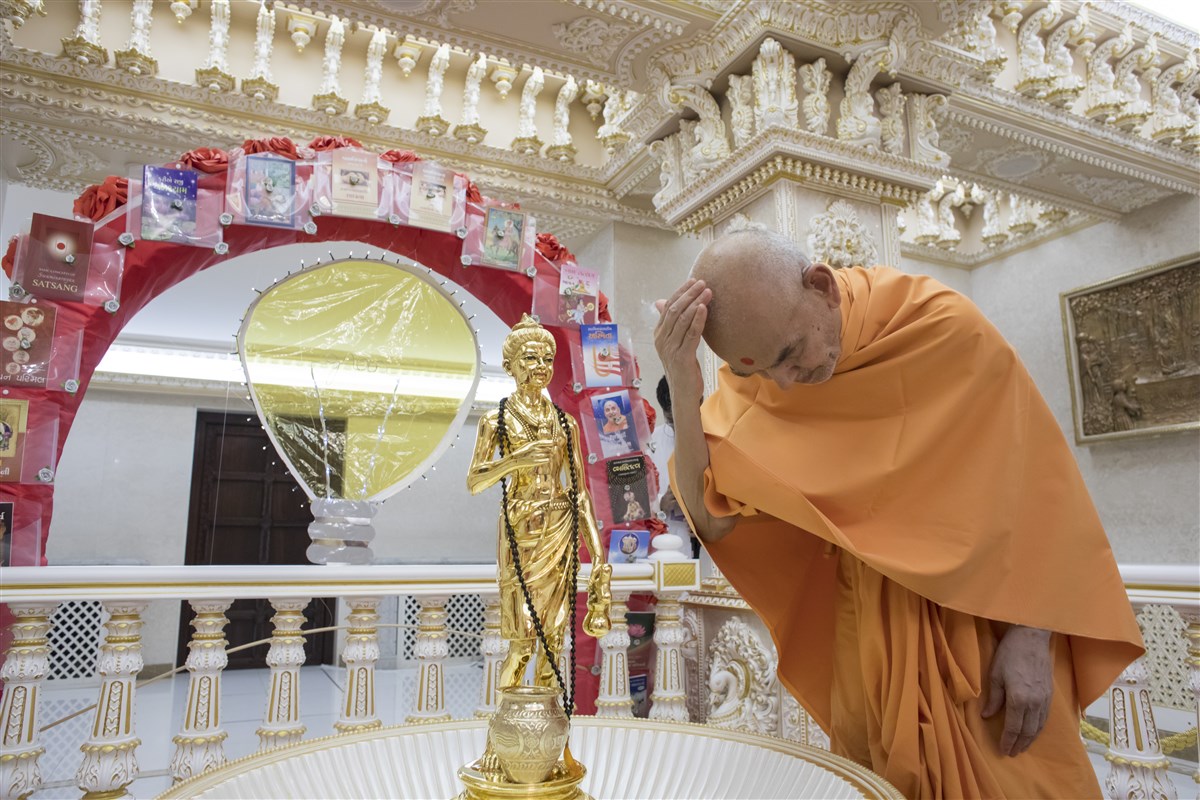 Swamishri applies the holy water of the abhishek upon his head