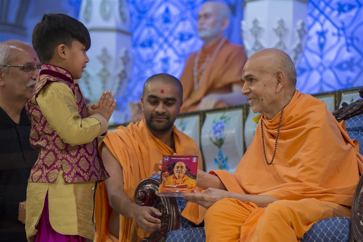 Swamishri blesses a child from Paris, accepting his invitation to grace Europe