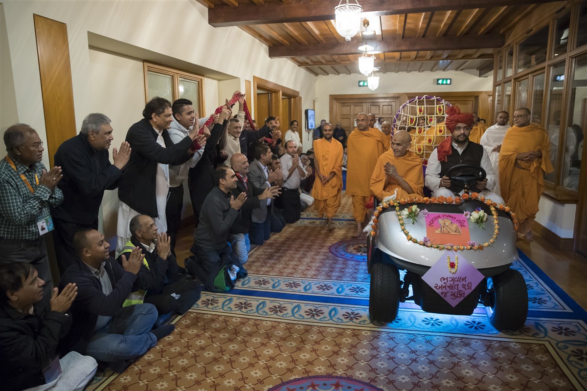 Swamishri greets devotees on his way to the assembly hall