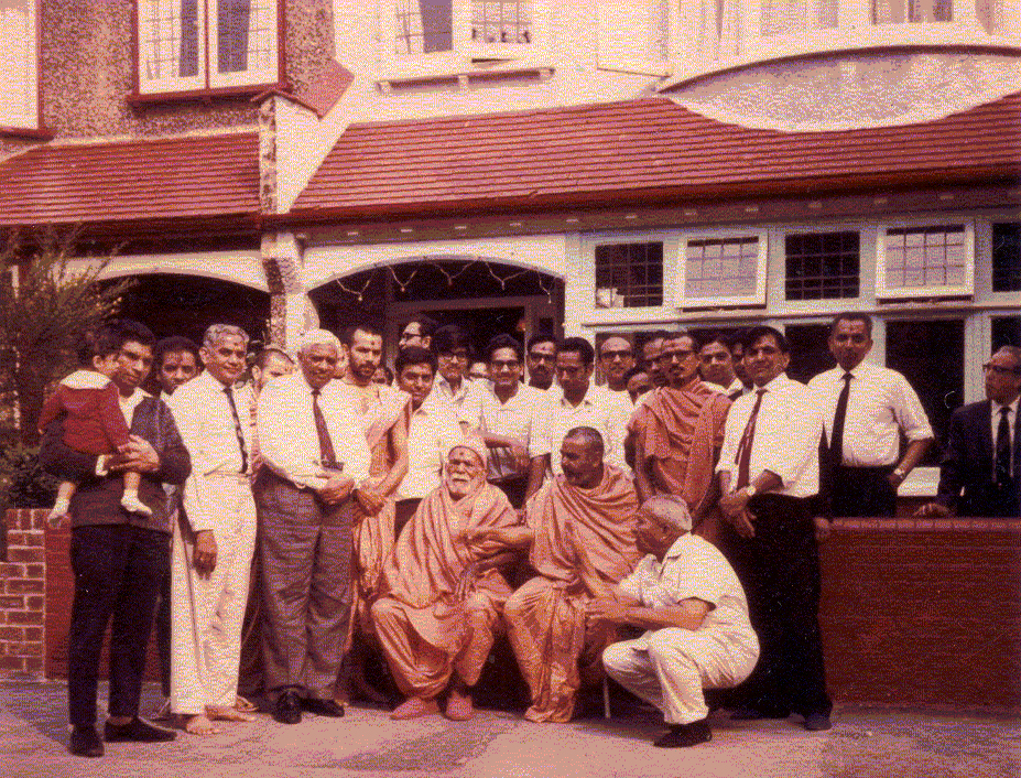 Yogiji Maharaj with Pramukh Swami, Mahant Swami and devotees outside the same house, in 1970