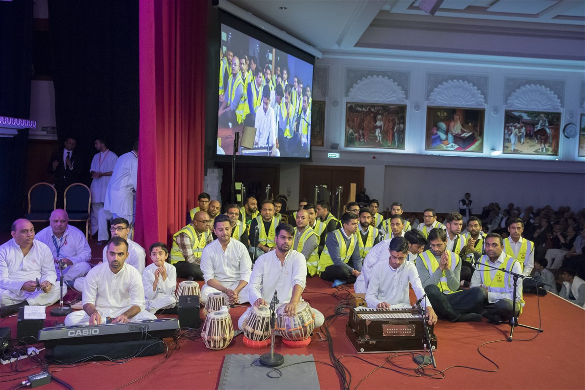 Volunteers sing in Swamishri's puja