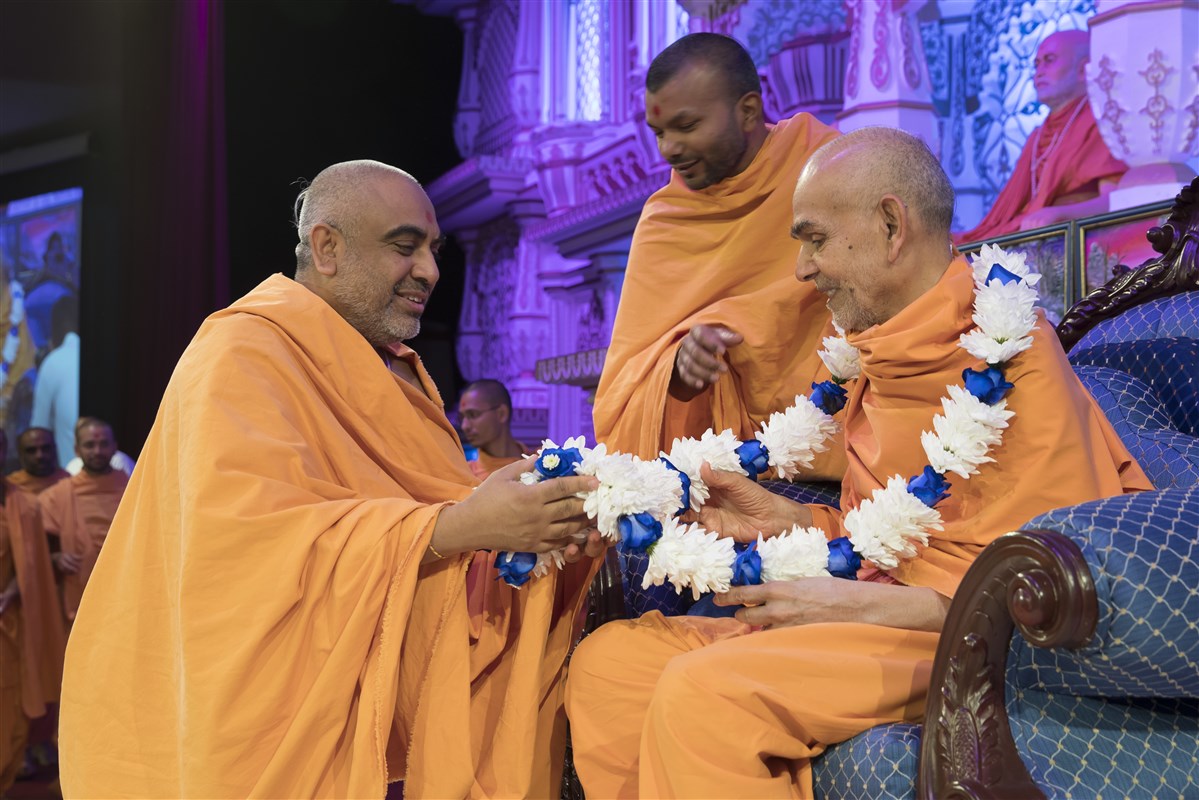 Yogvivekdas Swami honours Swamishri with a fresh flower garland