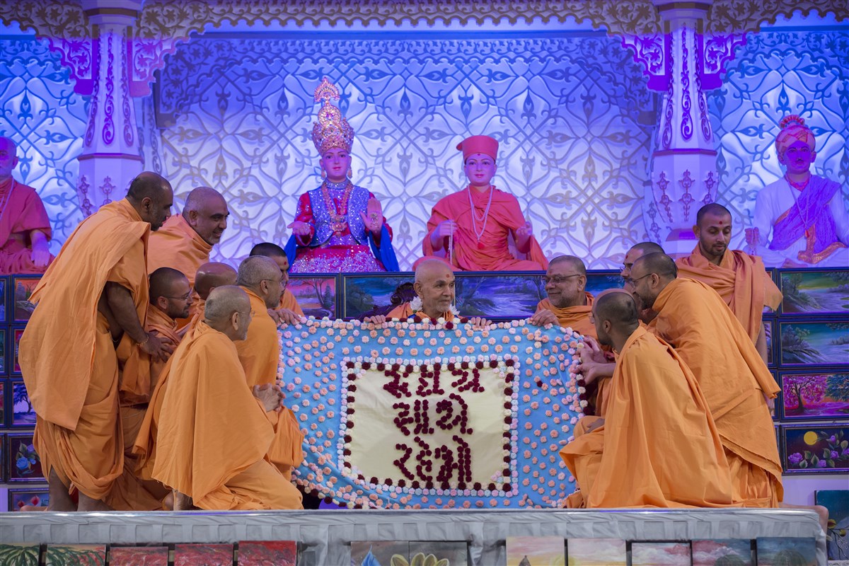 Swamis offer Swamishri a decorative shawl