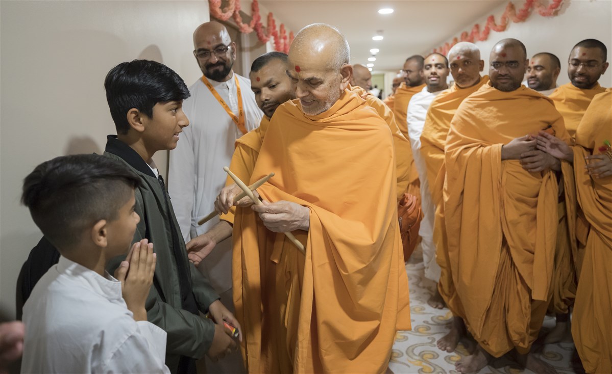 Swamishri blesses a child's drumsticks