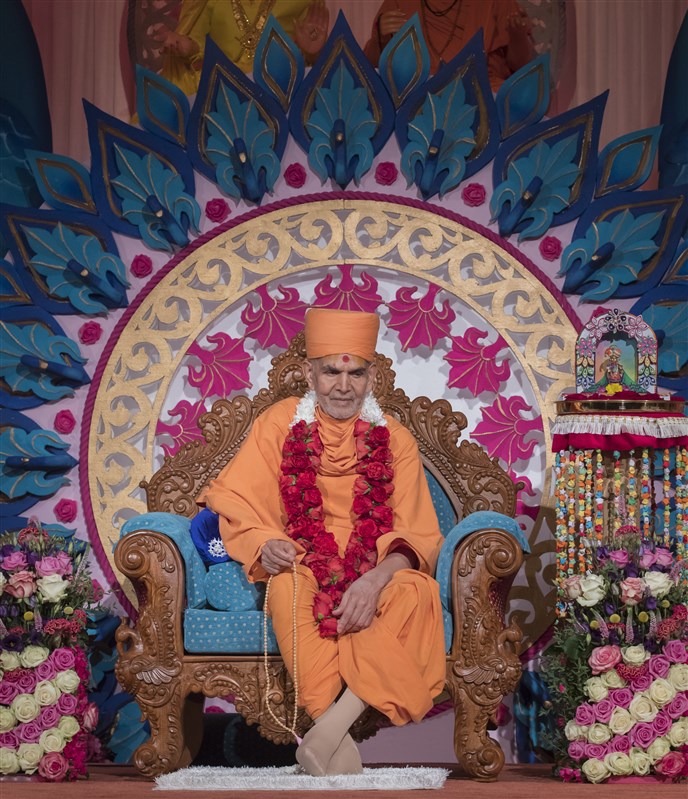 Swamishri is adorned with a pagh, chandan archa and a garland of fresh roses