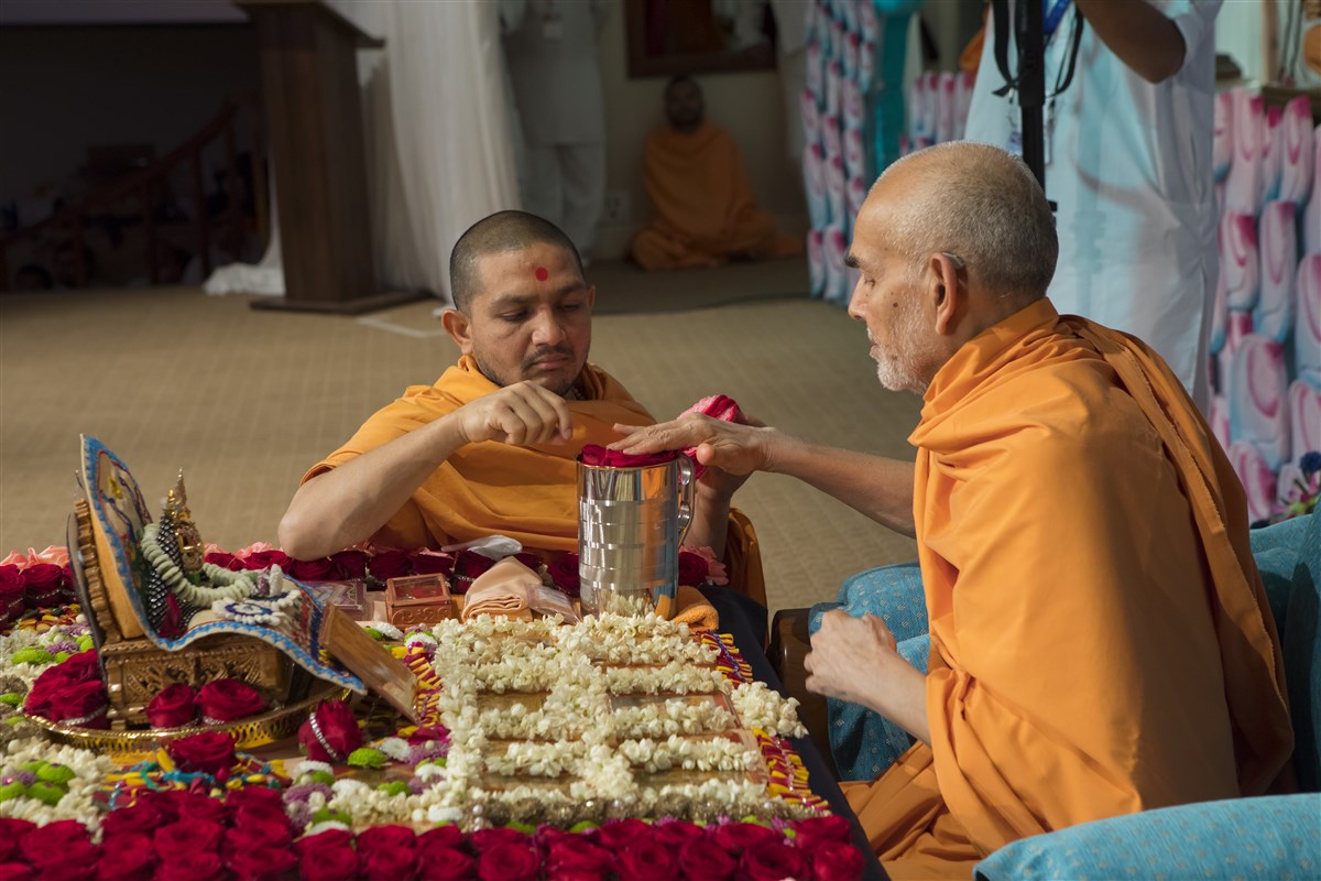Swamishri sanctifies water with roses offered to the murtis in his puja