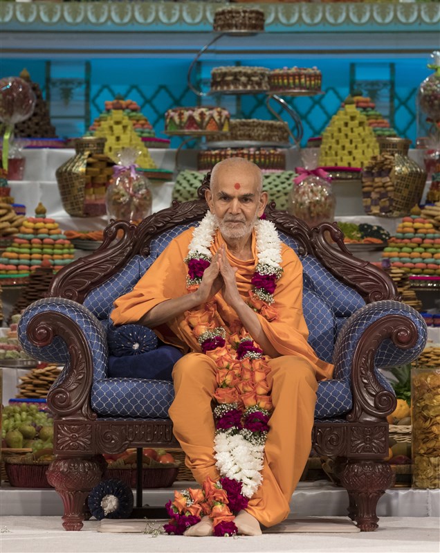 Swamishri is honoured with a garland of fresh flowers