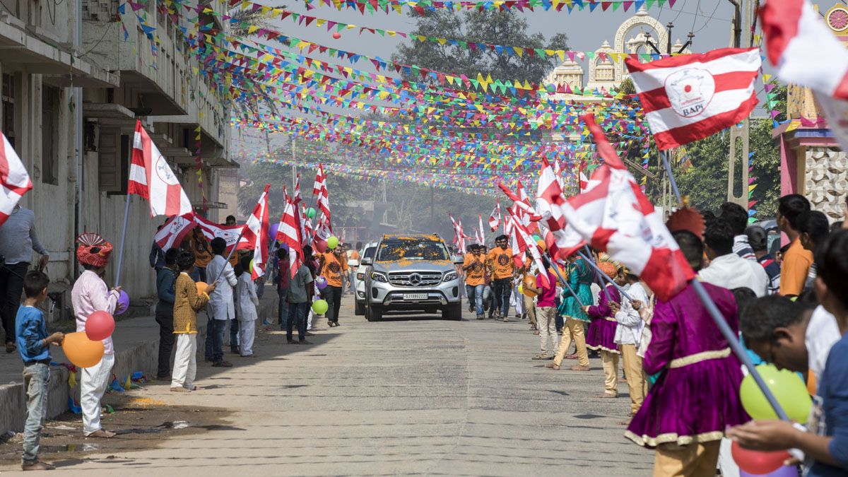Devotees with BAPS flags welcome Param Pujya Mahant Swami Maharaj 