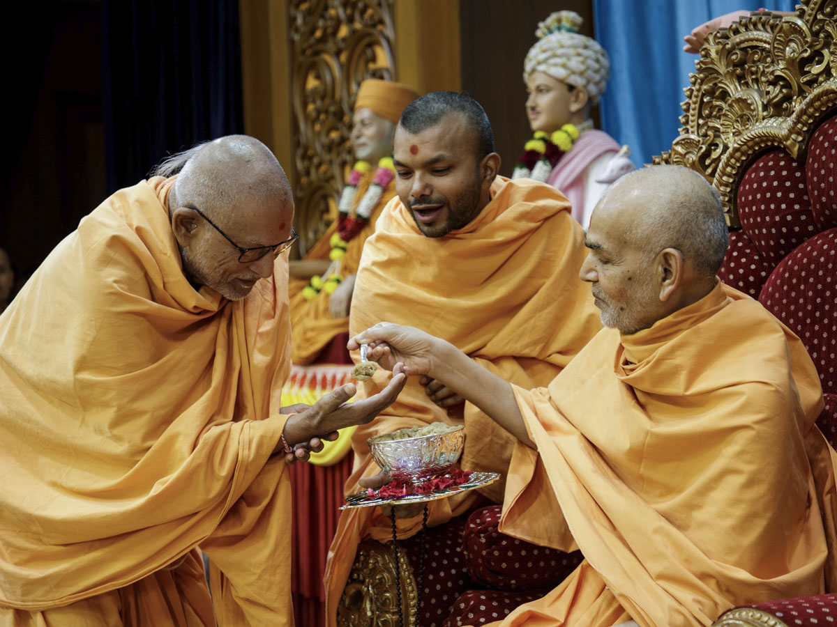 Swamishri gives prasad to Pujya Bhaktipriya Swami