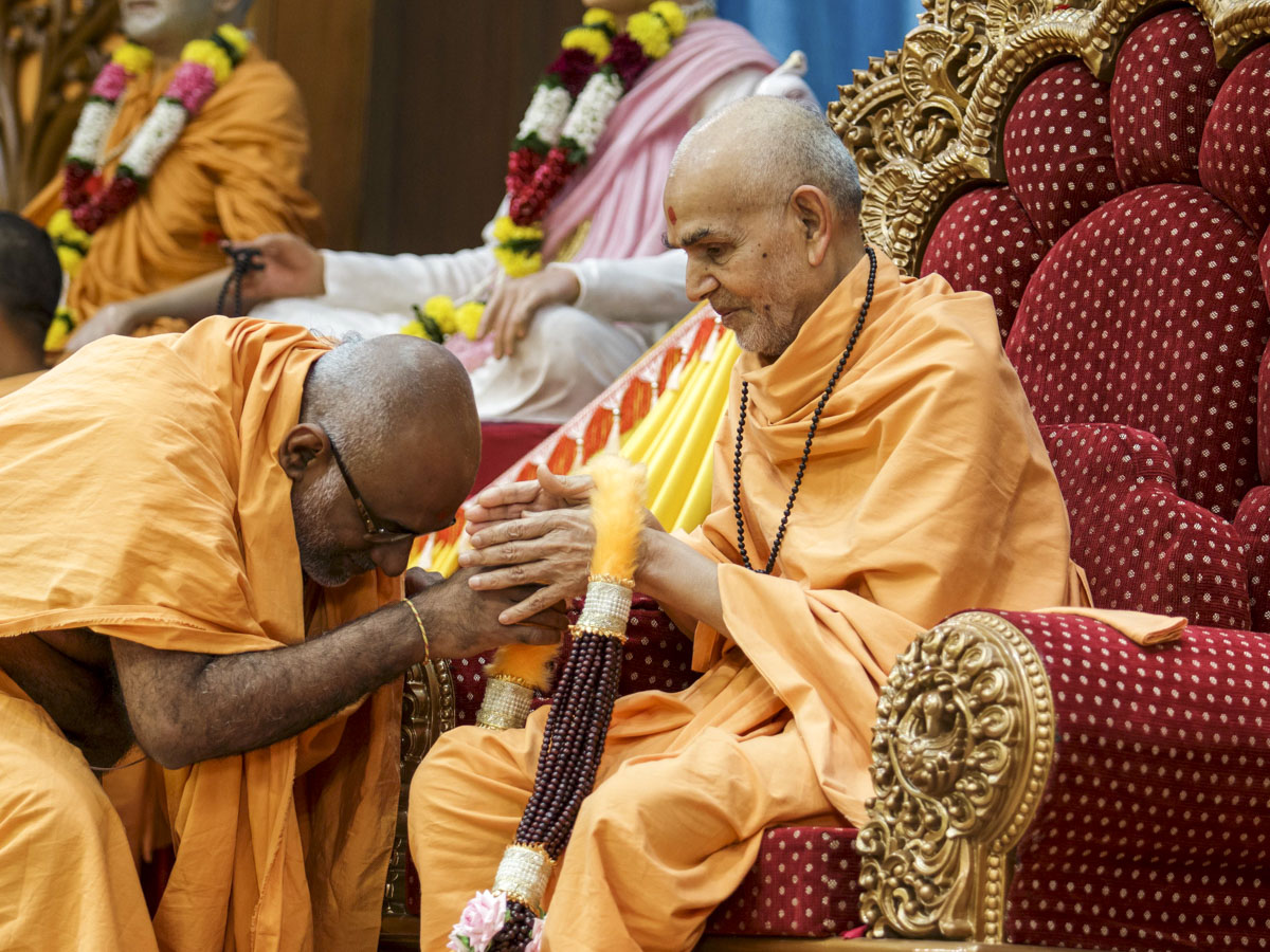 Abhayswarup Swami honors Swamishri with a garland