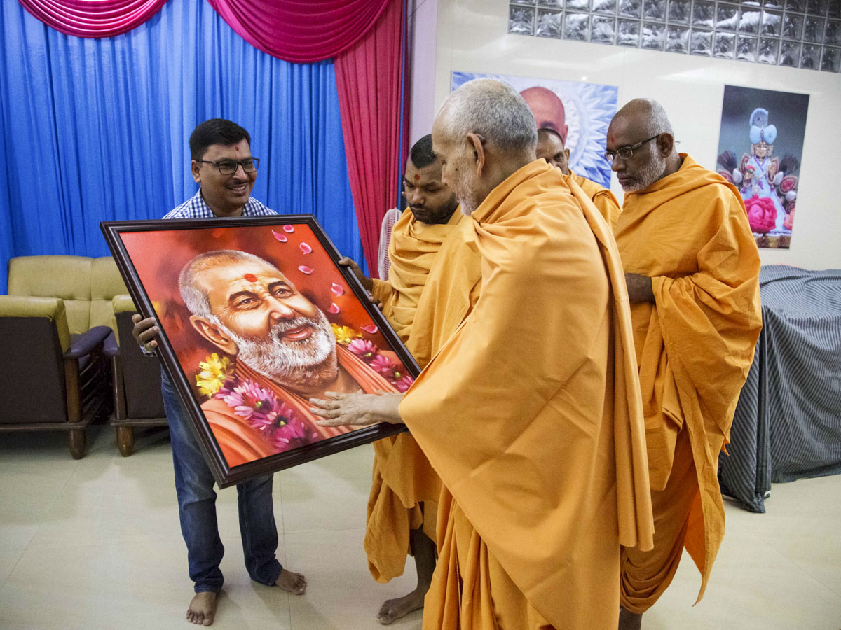 Swamishri sanctifies a painting of Pramukh Swami Maharaj