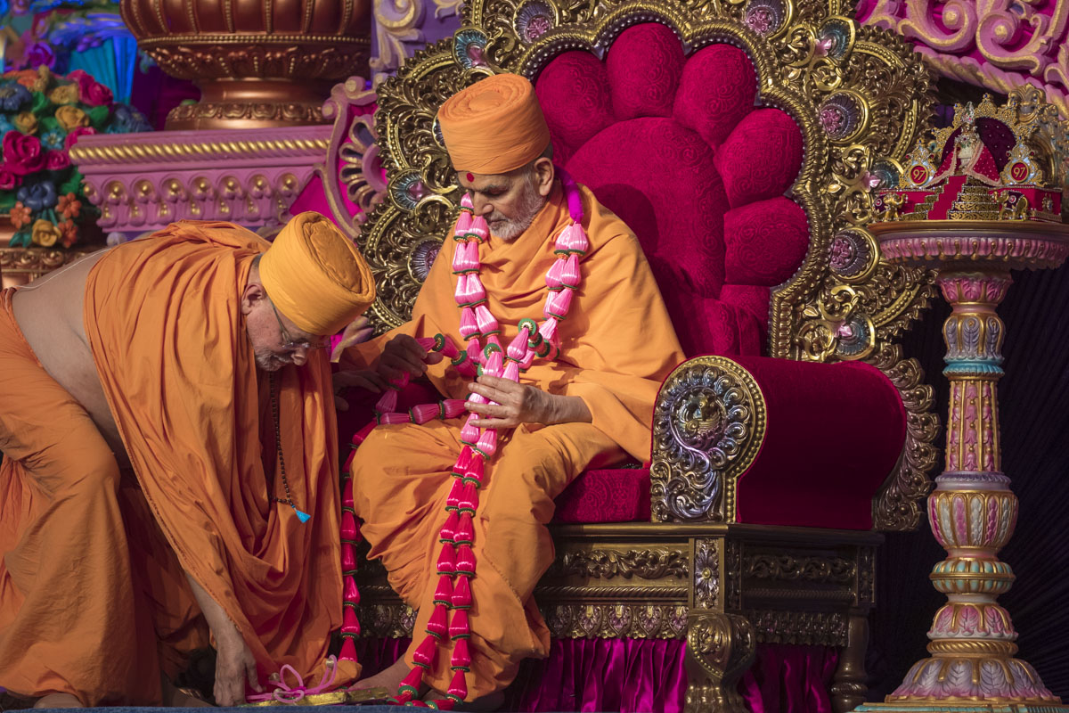 Pujya Ishwarcharan Swami honors Swamishri with a garland