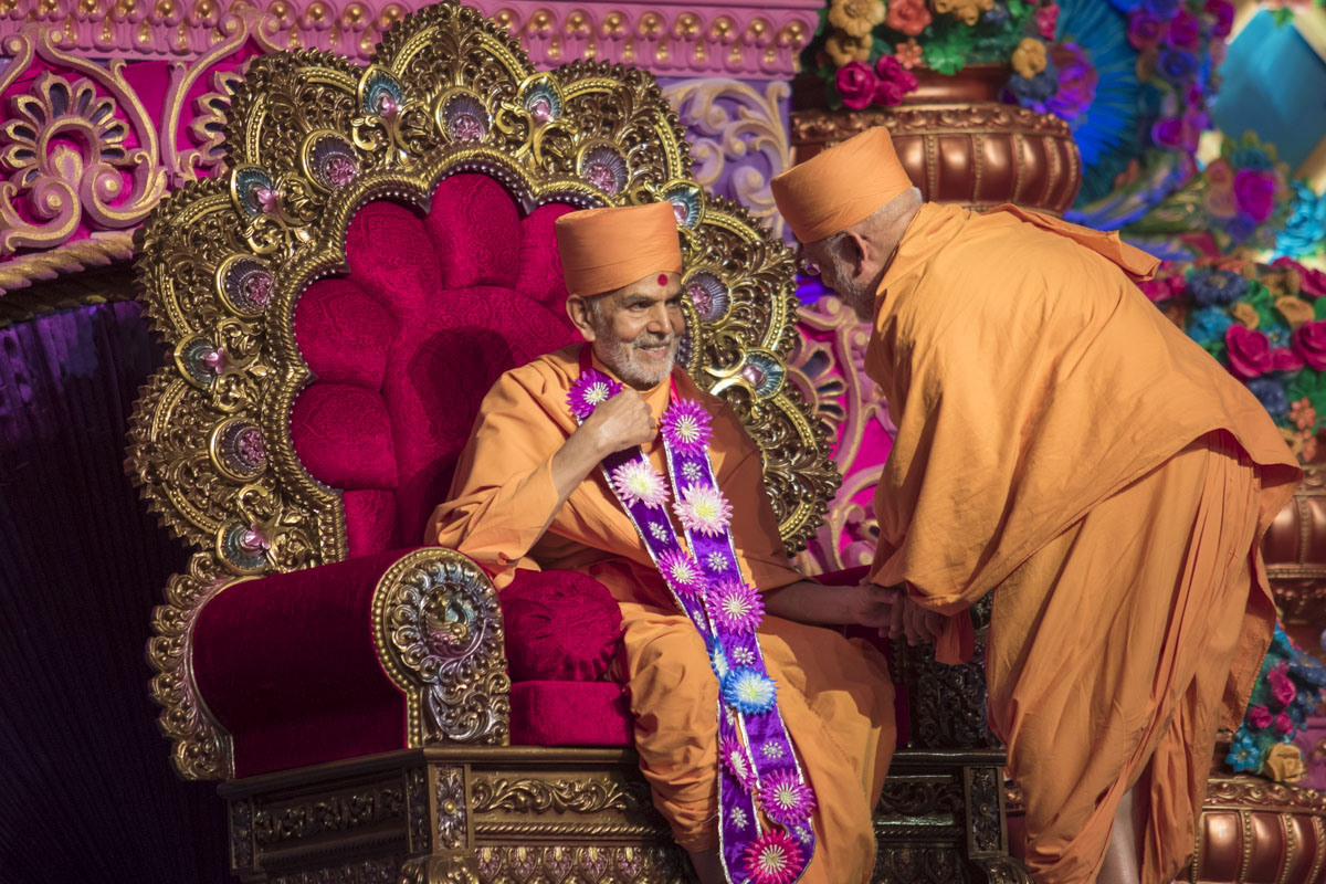 Pujya Ghanshyamcharan Swami honors Swamishri with a garland