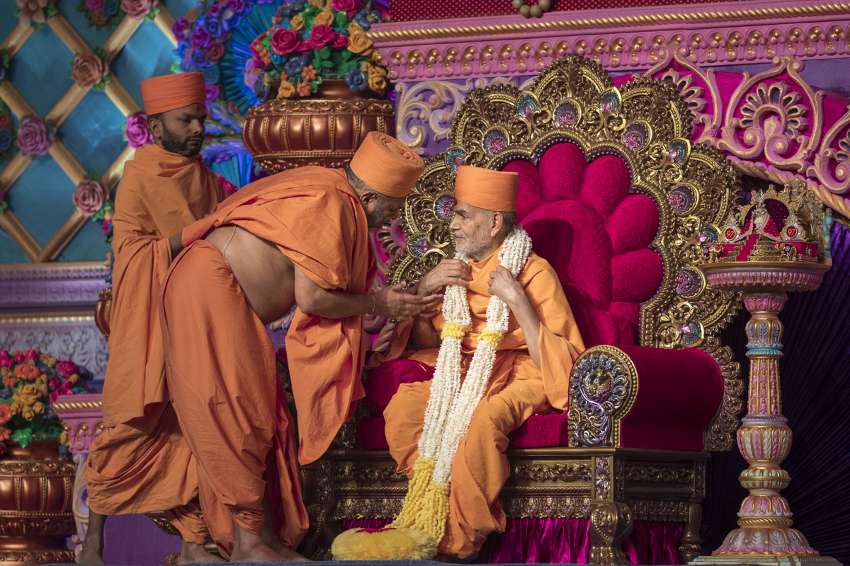 Bhagwatcharan Swami honors Swamishri with a garland