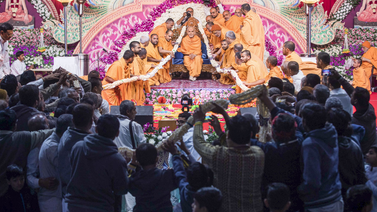 Sadhus and devotees honor Swamishri with a garland