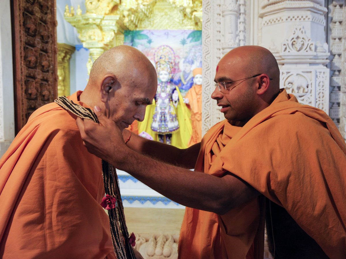 A sadhu honors Swamishri with a garland