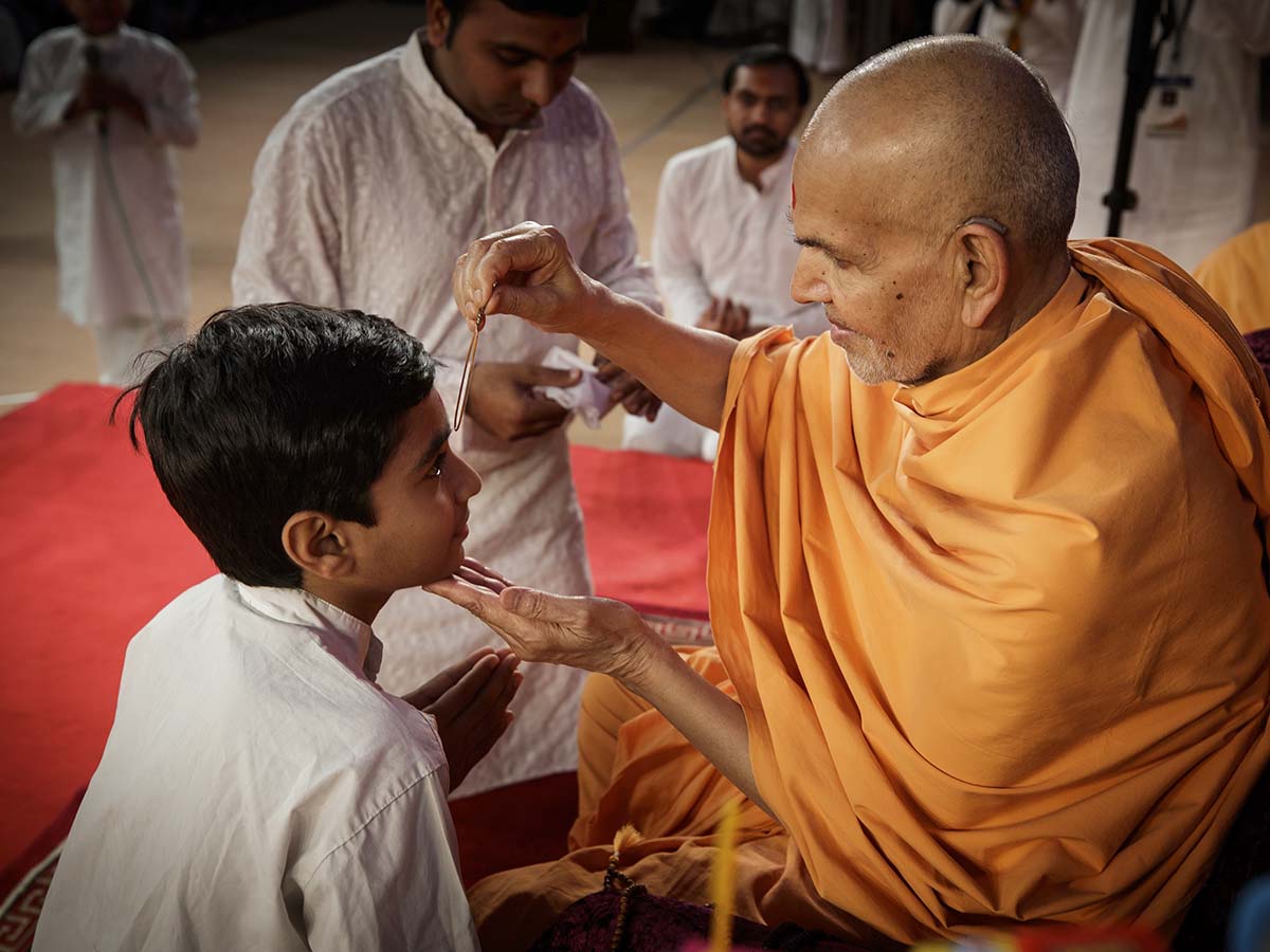 Swamishri applies tilak to a child