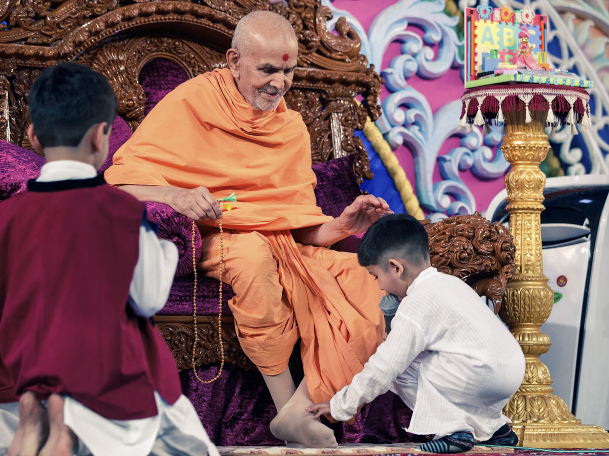 A child bows at the feet of Swamishri