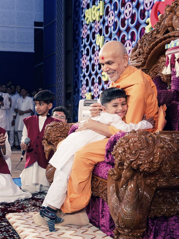A child embraces Swamishri