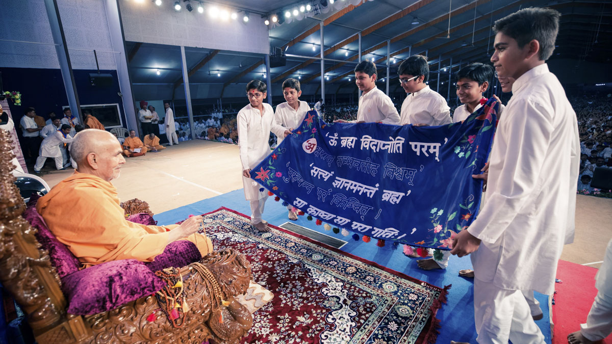 Children display a banner before Swamishri
