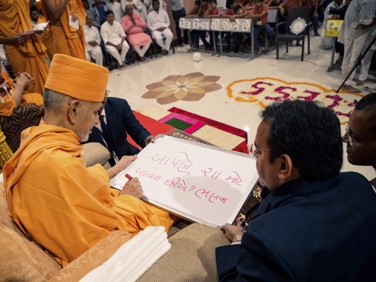 Swamishri writes blessings to students on a board
