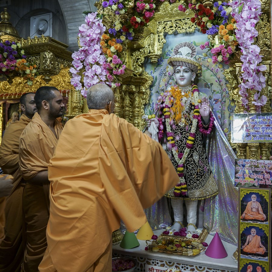 Swamishri showers flower petals on Shri Ghanshyam Maharaj
