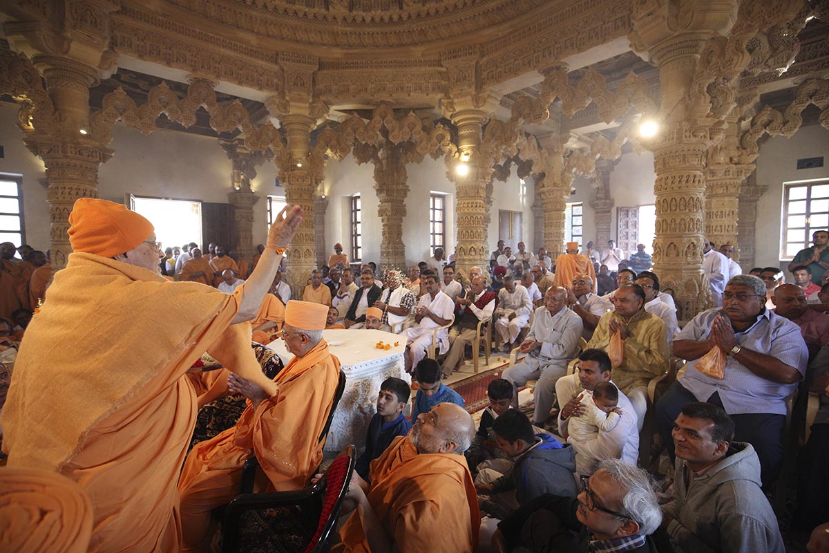 Pujya Ishwarcharan Swami showers sanctified rice grains on devotees