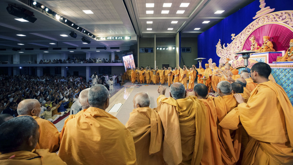 Swamishri joins hands with swamis and devotees in a gesture of unity