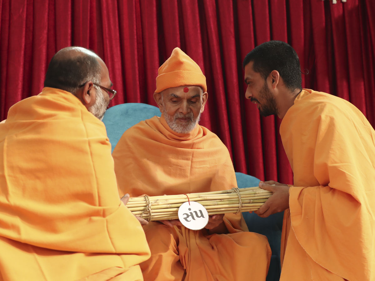 Sadhus present a bundle of sticks to symbolize unity