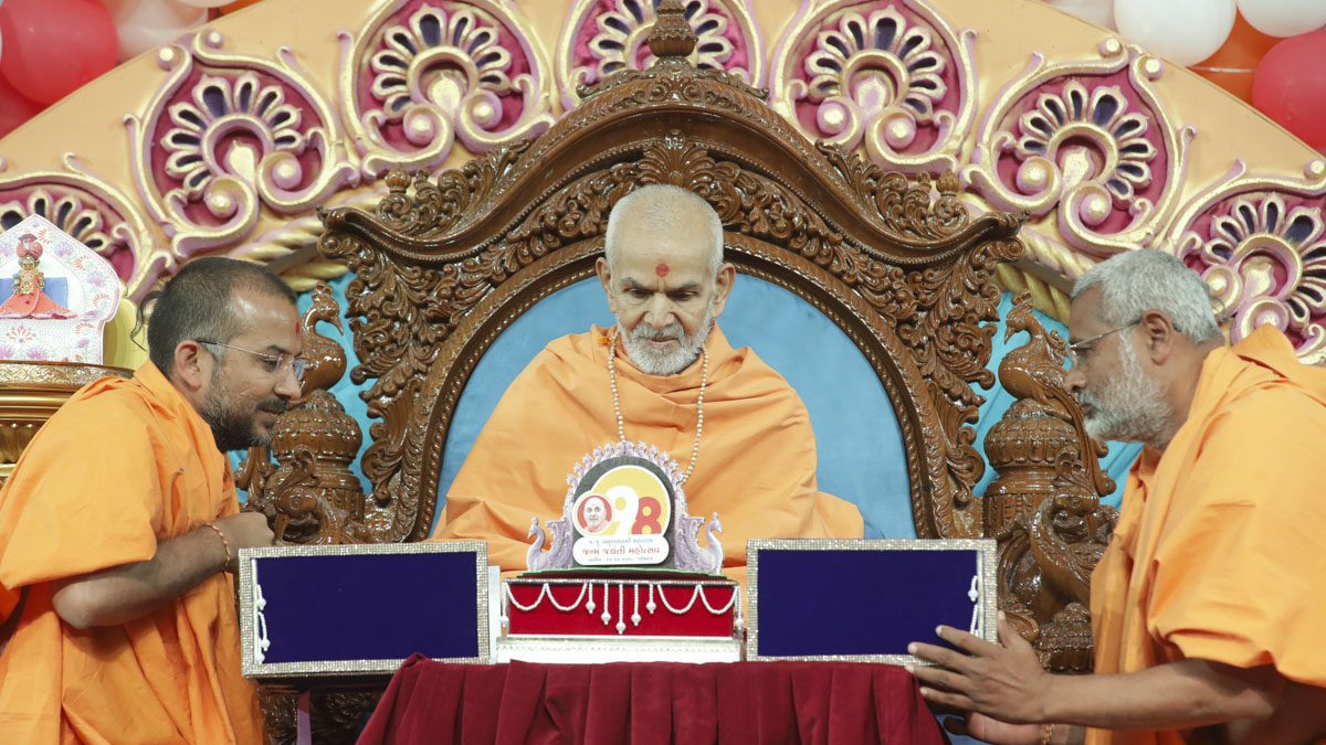 Brahmatirth Swami (right) and Apurvamuni Swami present a special invitation to Swamishri for the 98th birthday celebrations of Brahmaswarup Pramukh Swami Maharaj