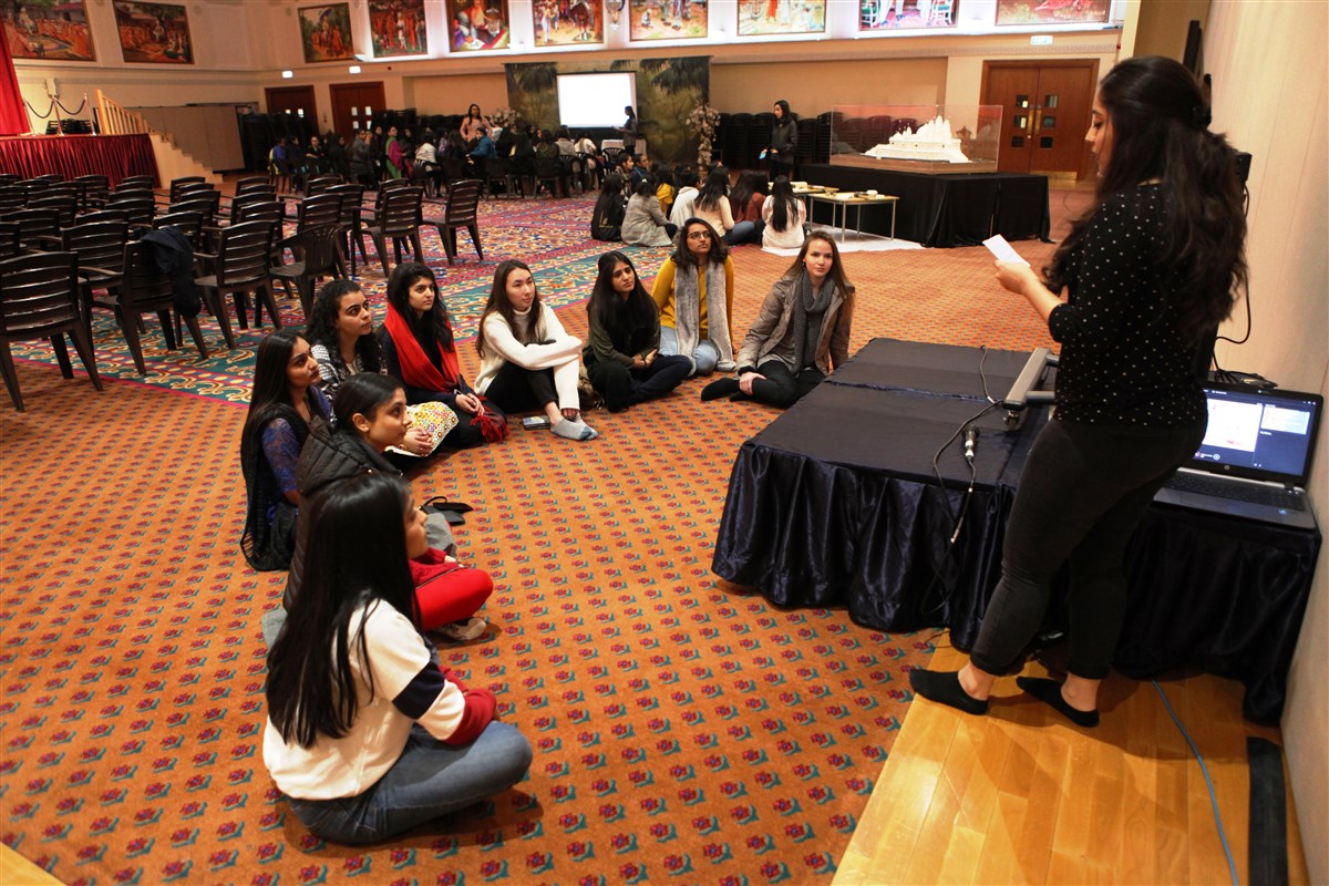 Delegates listen to a youth volunteer presenting a workshop on seva