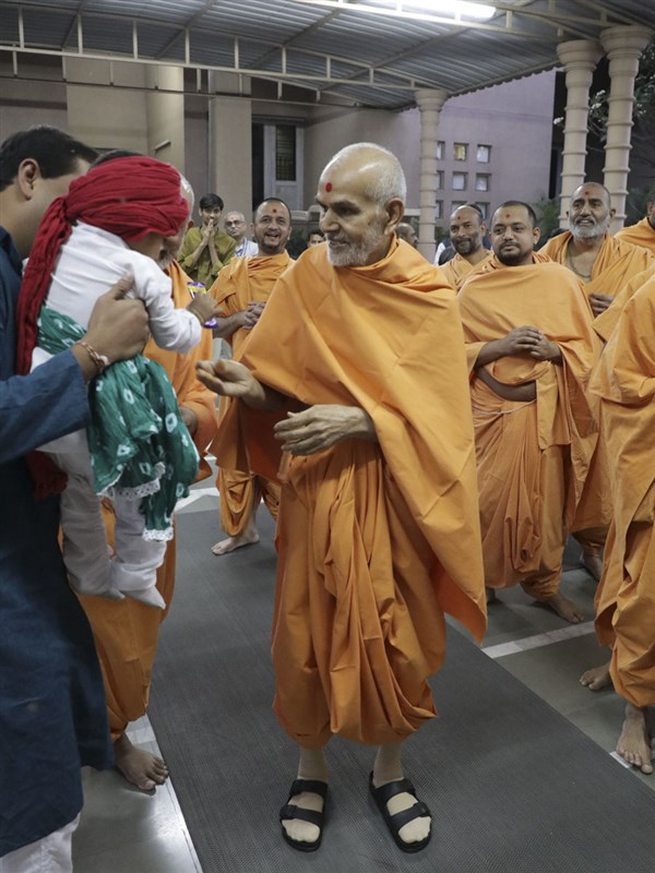A child interacts with Swamishri