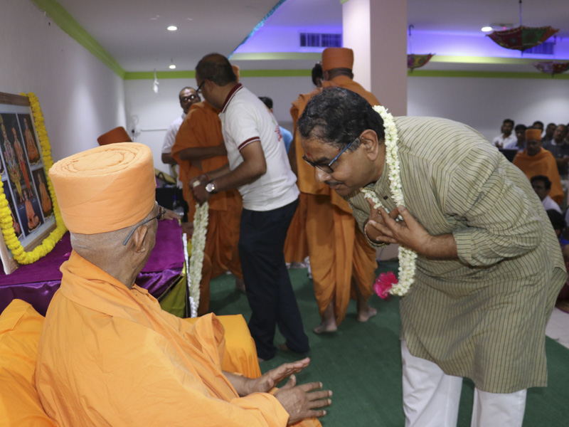 Devotees welcome Pujya Doctor Swami with a garland