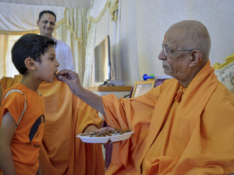 Pujya Doctor Swami gives prasad to a child