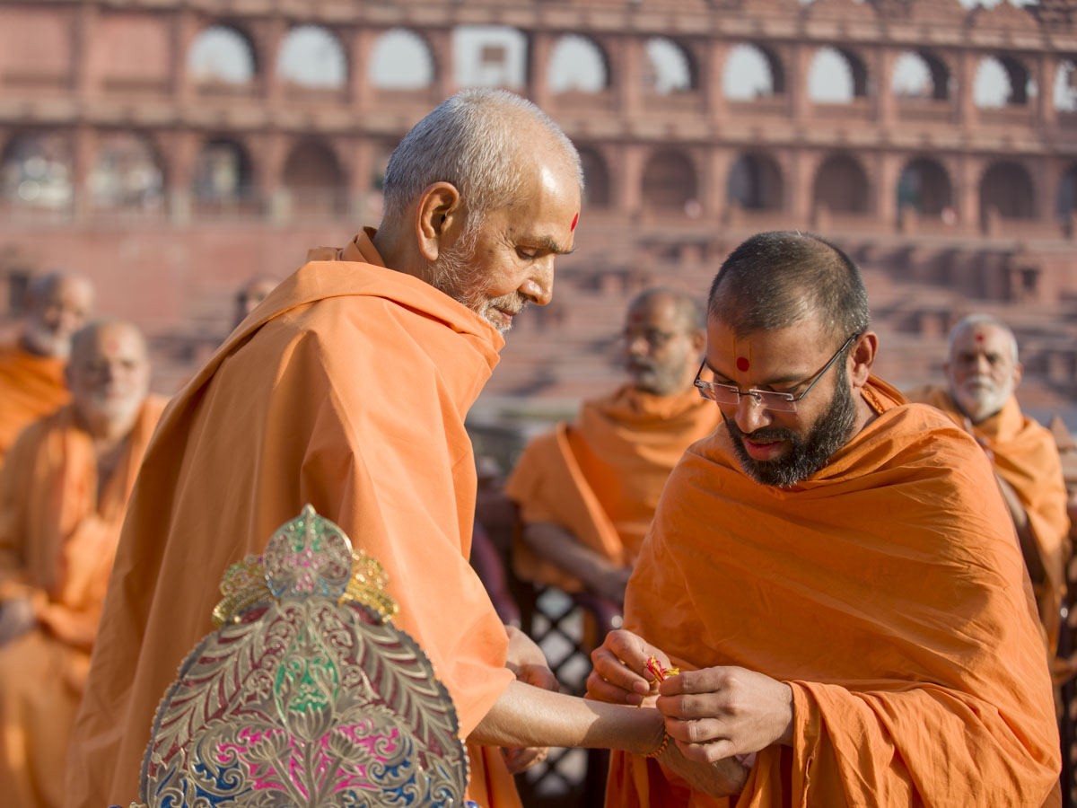 Kirtisagar Swami ties a nadachhadi to Swamishri