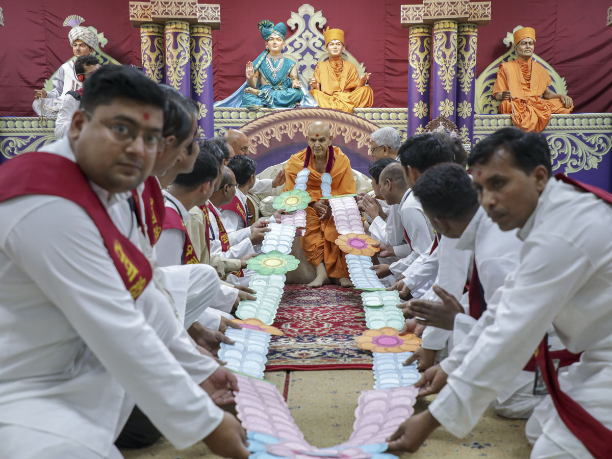 Volunteers honor Swamishri with a garland