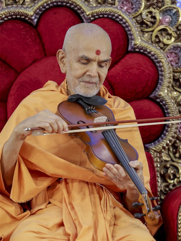 Swamishri plays a violin during the Bal Din assembly