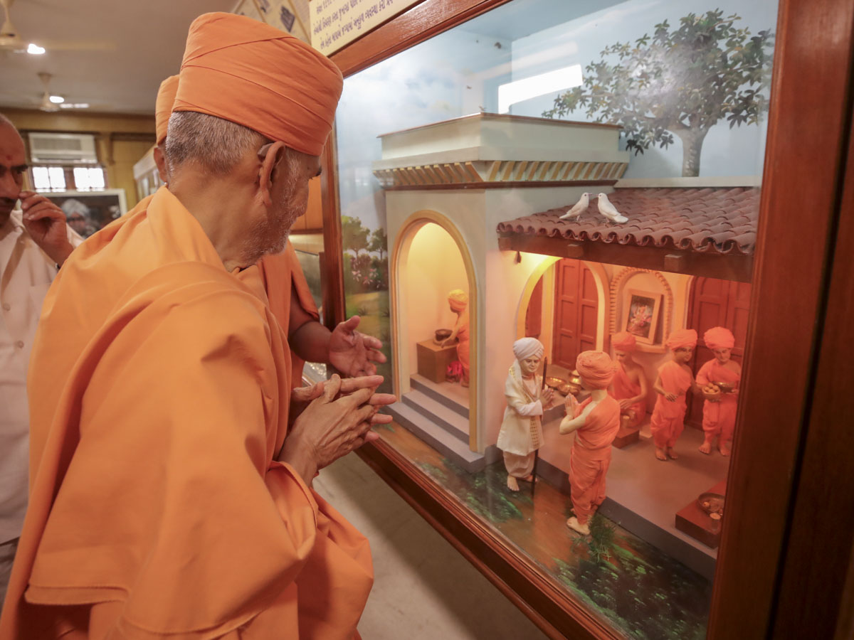 Swamishri observes a display depicting the meeting between Aksharbrahman Gunatitanand Swami and Shri Jalaram Bapa in Virpur