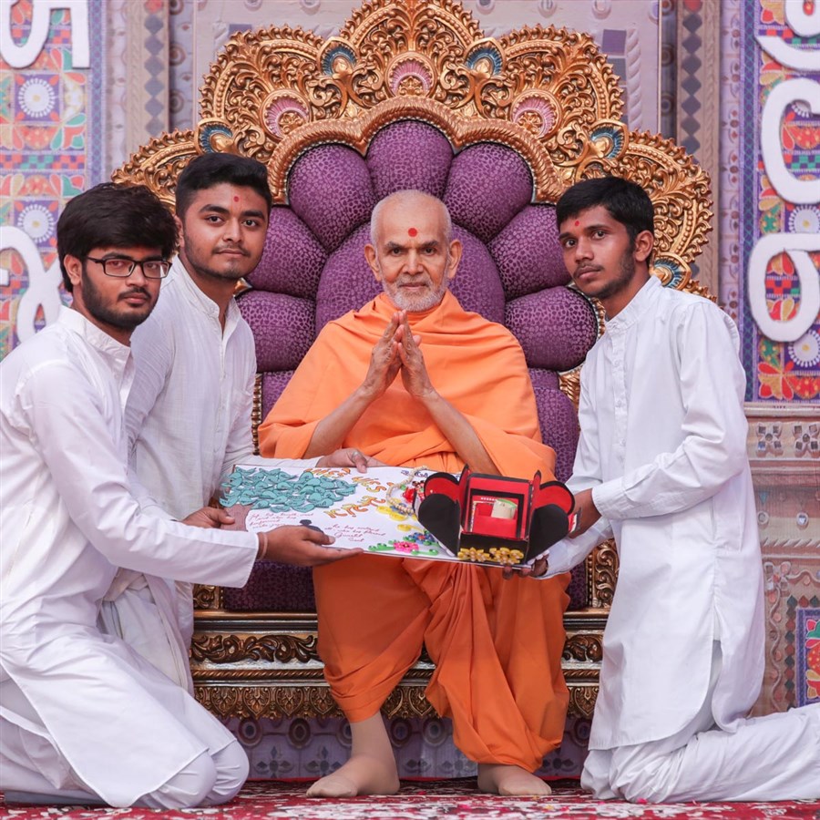 Youths present a card to Swamishri