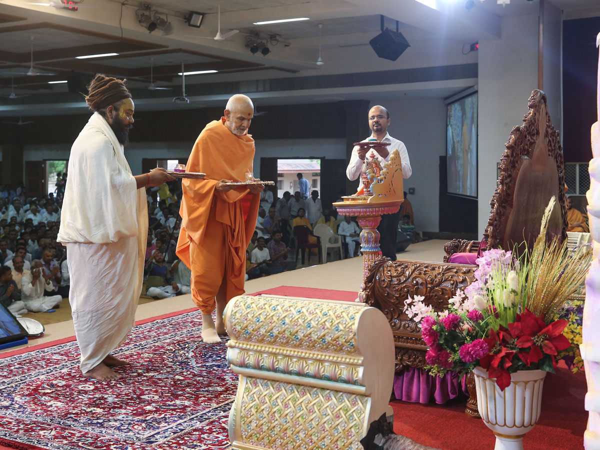 Swamishri and invited guests perform the evening arti
