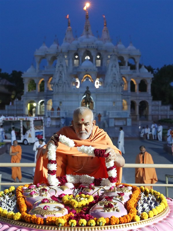 Swamishri places a garland at Brahmaswarup Pramukh Swami Maharaj's samadhi