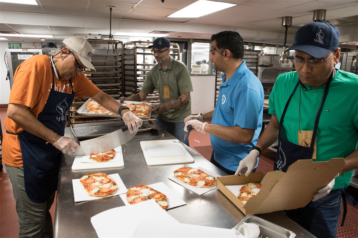 Kitchen volunteers prepare margherita pizzas for the delegates