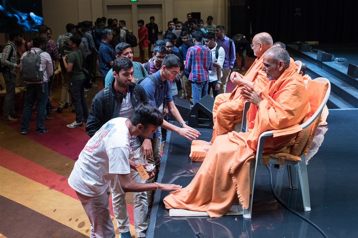 Pujya Ishwarcharandas Swami and Pujya Anandswarupdas Swami greet youth with folded hands