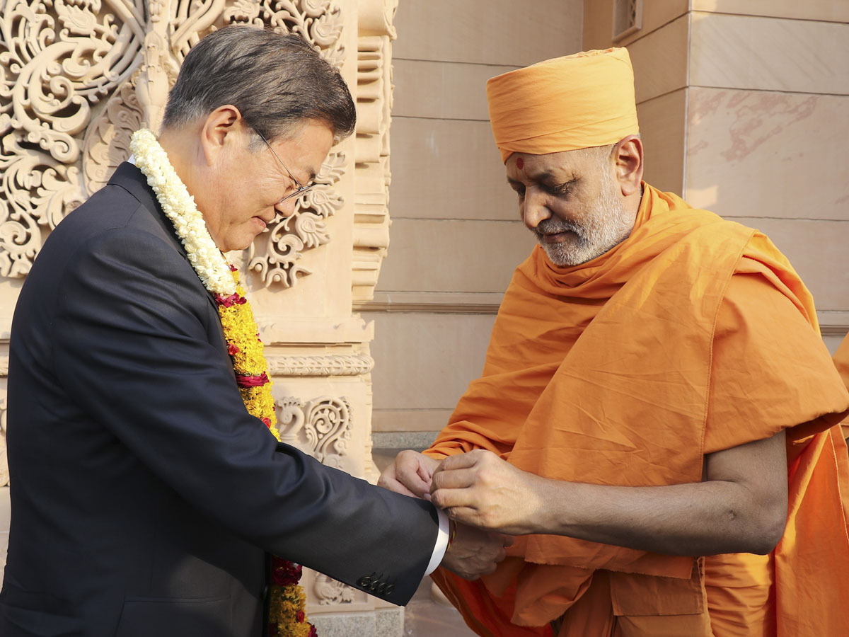 Dharmavatsal Swami welcomes President Moon to Swaminarayan Akshardham in a traditional manner by tying a kalava (sacred thread)