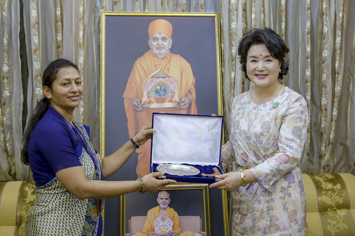 A senior volunteer presents a gift to South Korean First Lady Kim